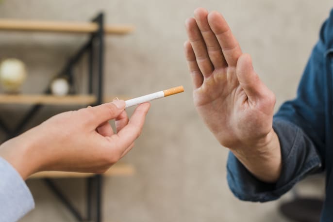 Homem recusa um cigarro com um gesto de mão.