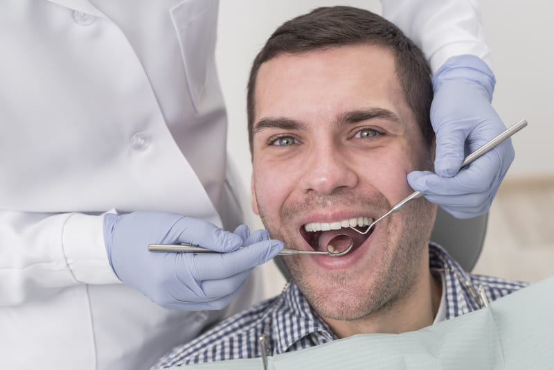 Homem no dentista, realizando uma consulta de rotina.