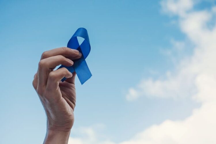 Um homem segurando uma fita azul, simbolizando as campanhas do Novembro Azul.